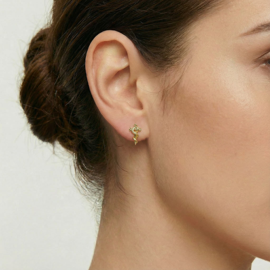 [Brand] 24K Gold Vermeil Snake Cross Stud on model, close-up earlobe jewelry shot.