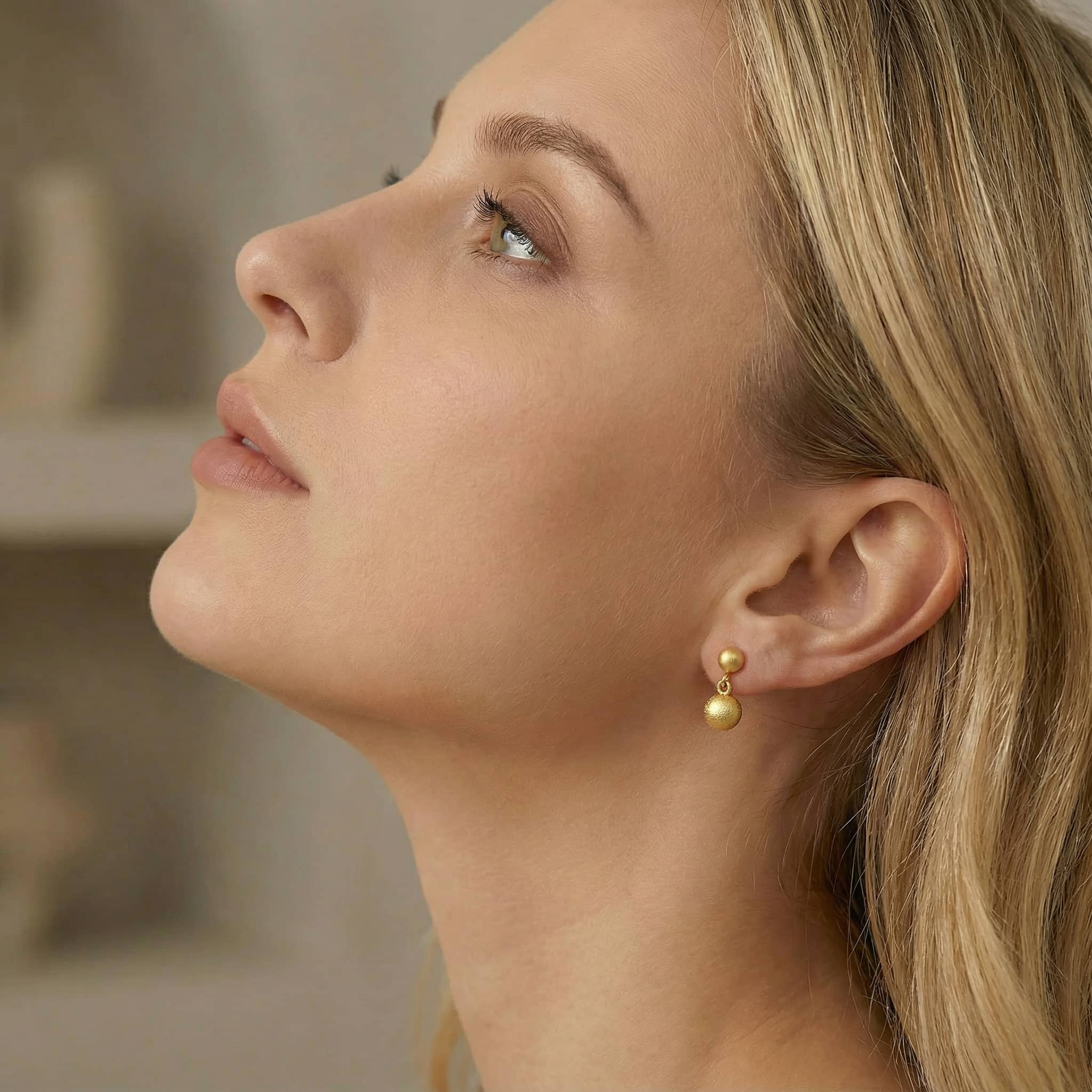 Model profile wearing 24K gold plated sterling silver drop bead earrings.