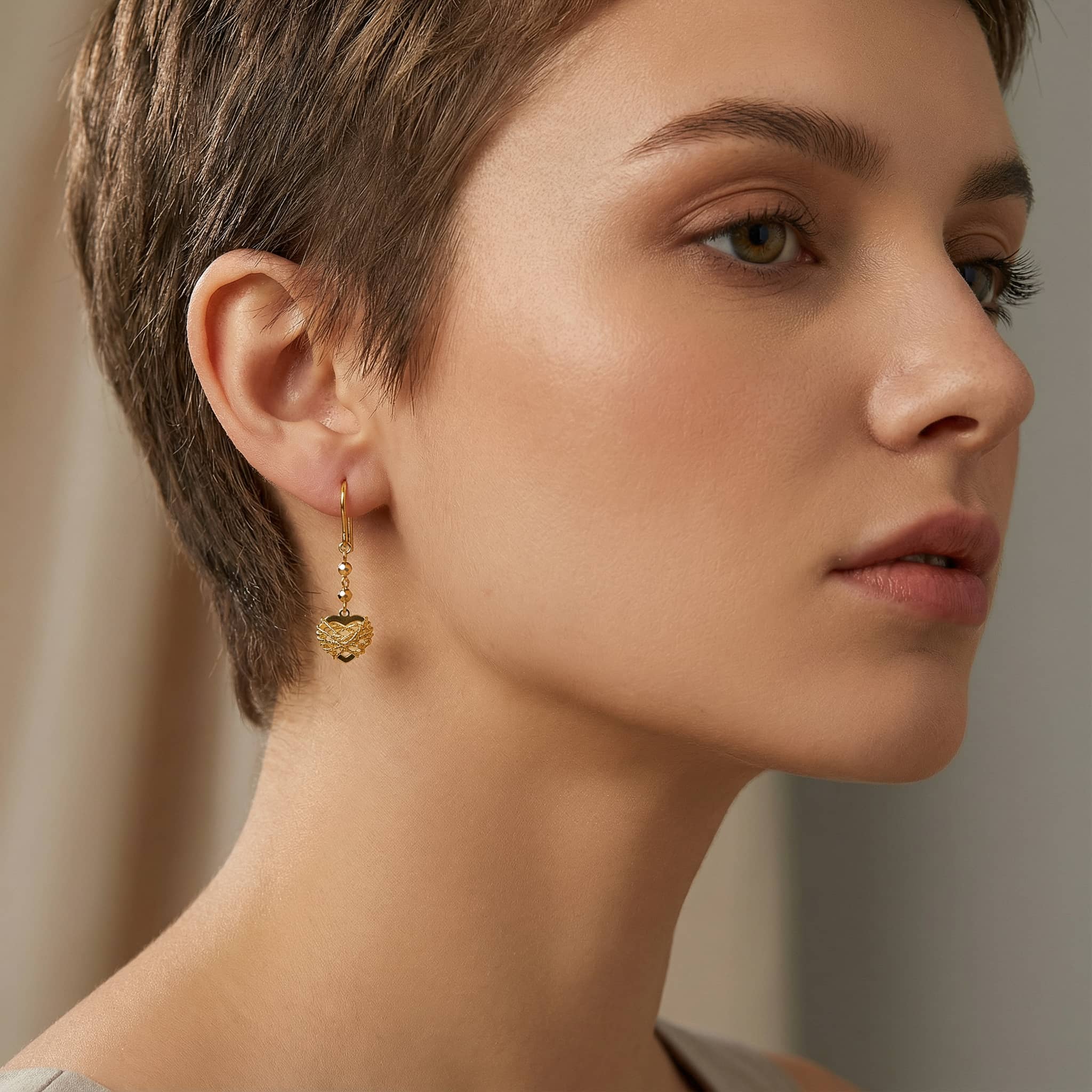Brand 18K Gold Heart Dangle Earrings worn by a woman, elegant side view lifestyle shot.