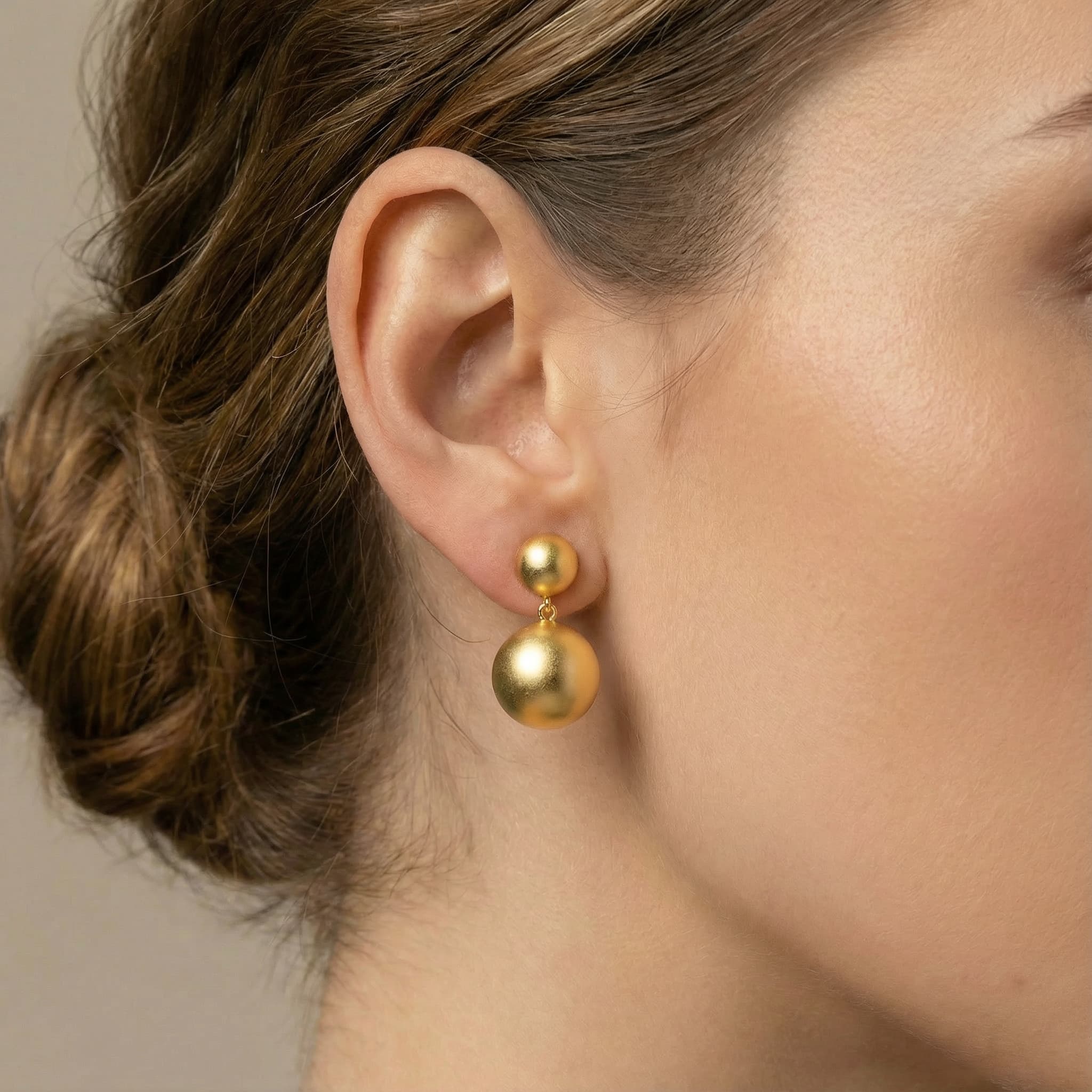 Close up of 24K gold plated silver double ball earrings on ear.