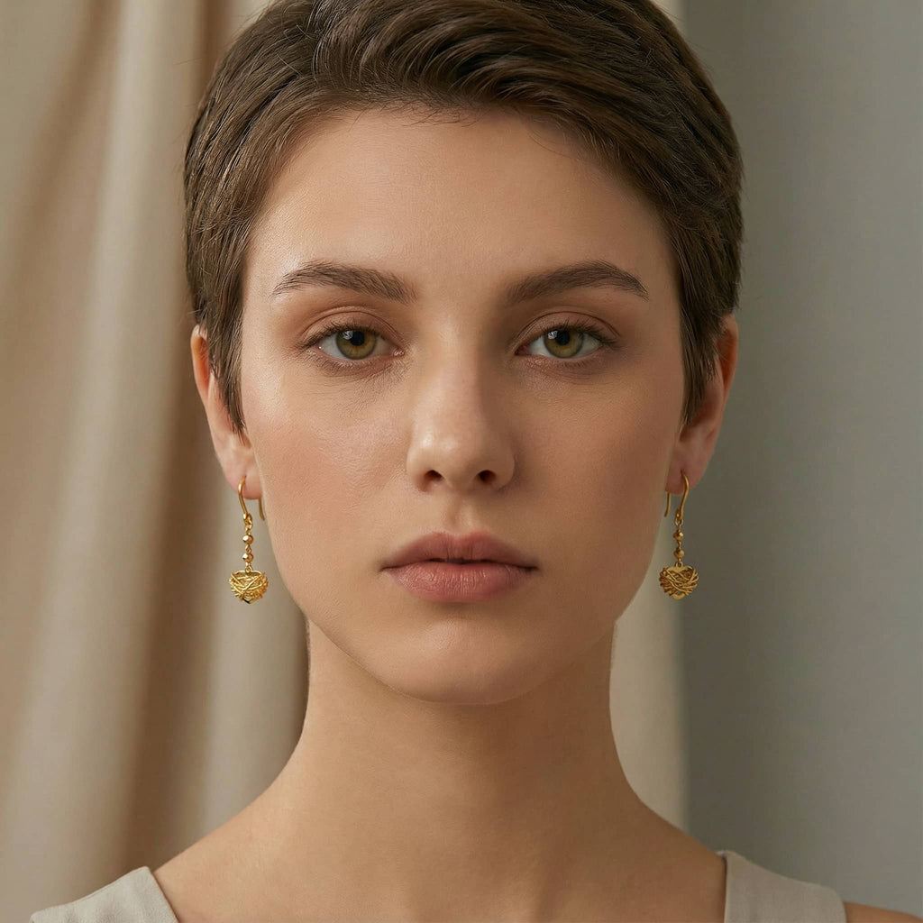 Brand Woven Heart Drop Earrings worn by a model, front view showing symmetrical gold jewelry style.