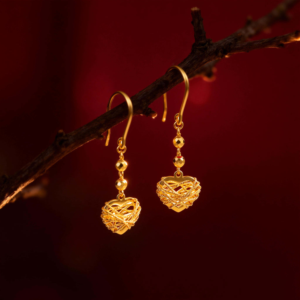 Brand Gold Woven Heart Drop Earrings on a dark branch background, luxury jewelry photography.